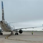 Frontier Airlines plane on the tarmac with another Frontier tail wing nearby