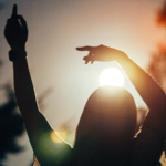 Silhouette of a woman standing outside as the Sun lowers as she contemplates her weekly horoscope for September 14-20, 2025