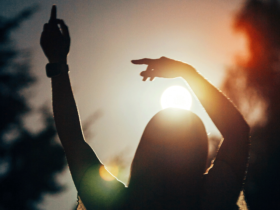 Silhouette of a woman standing outside as the Sun lowers as she contemplates her weekly horoscope for September 14-20, 2025