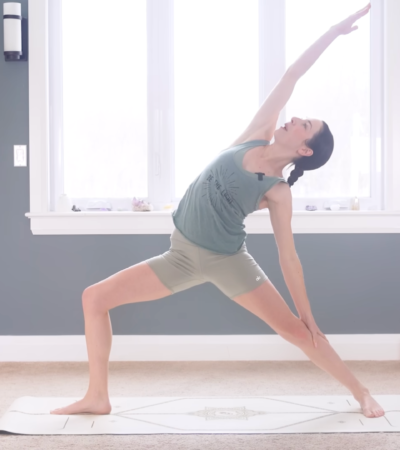 Woman in Reverse Warrior facing the long side of a mat and reaching her right arm alongside her head