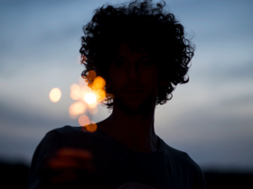 A silhouette of a woman at dusk holding a sparkler with the night sky behind her.