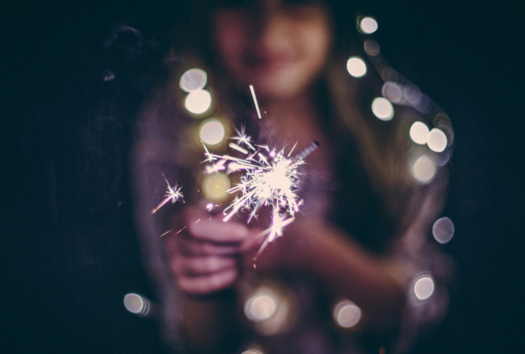 Girl holding sparkers and twinkle lights at night